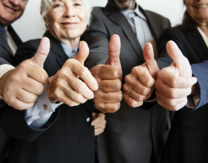 Group of businesspeople giving thumbs up, indicating a success-oriented team spirit.